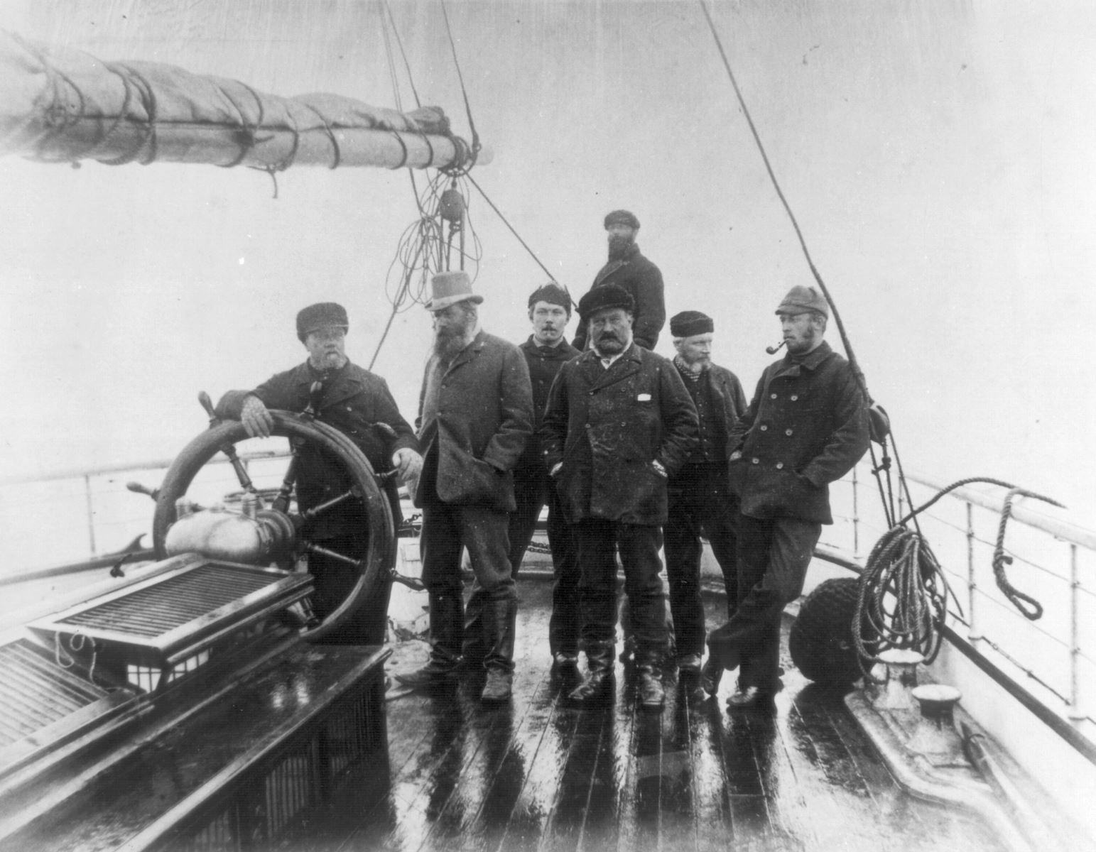 A group of men around the ships wheel on the boat