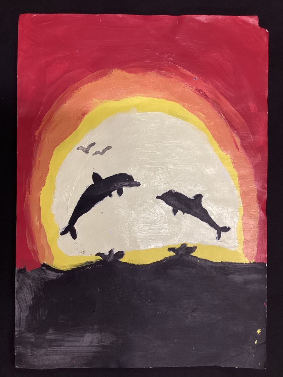dolphins leaping in front of a setting sun