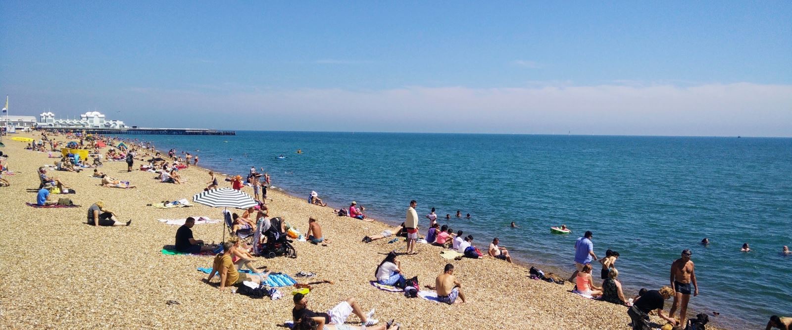People paddling whilst others relax on Southsea Beach