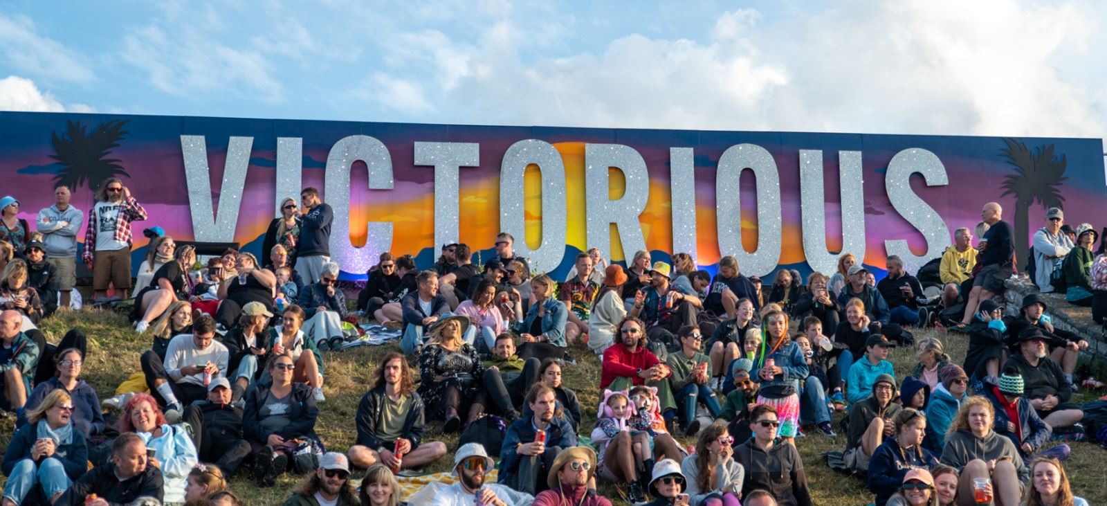 People sat on the embankment under the Victorious Festival sign