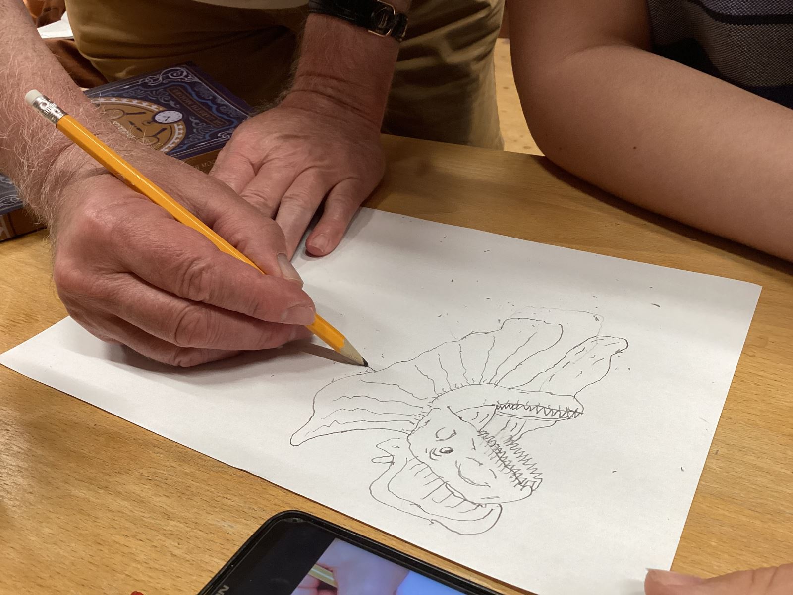 A person drawing a Dilophosaurus's head