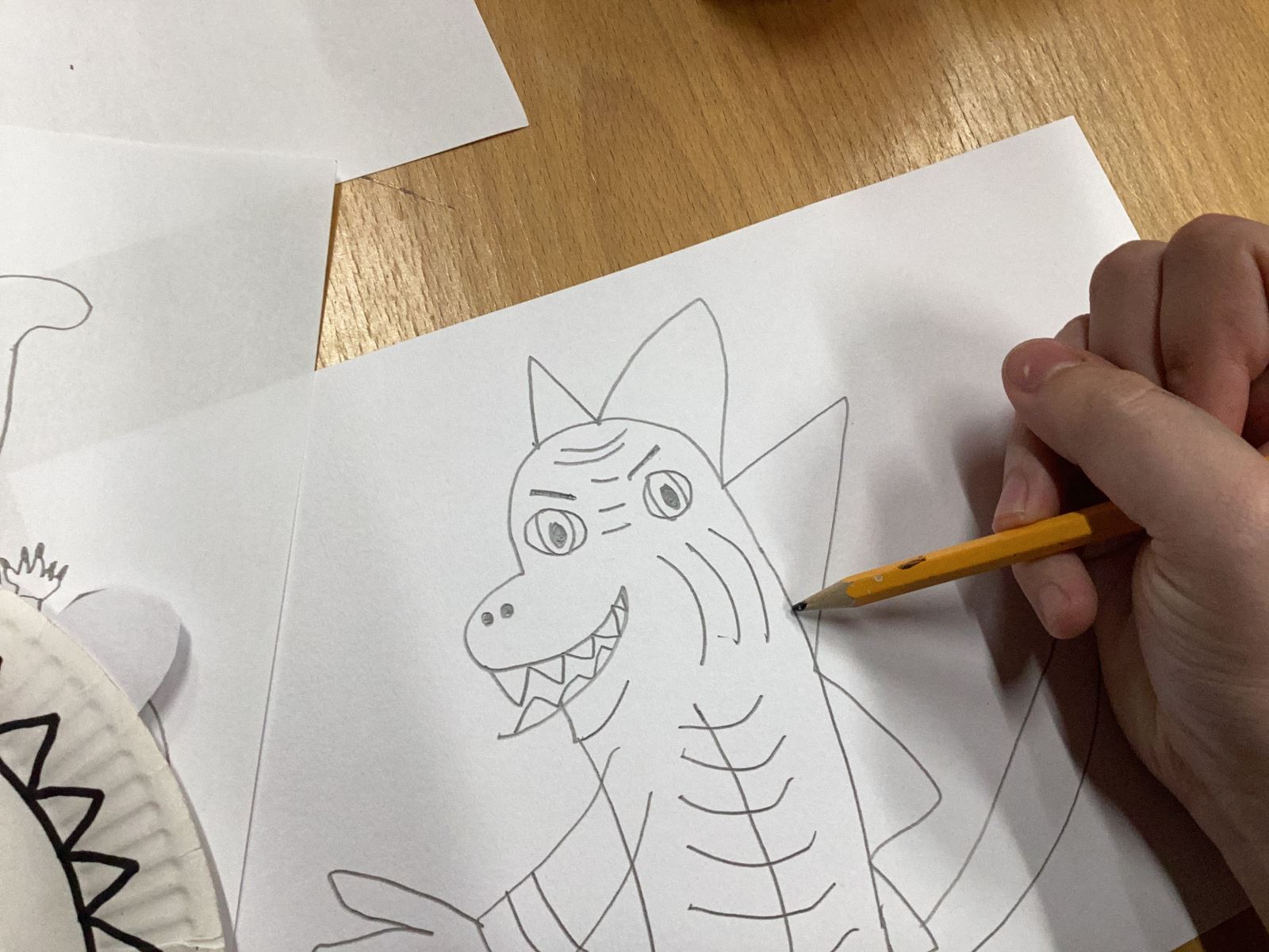 A person drawing a dragon looking dinosaur